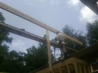 Carpenter setting a ridge beam over a new addition frame — Ice Dam Removal by Roofing Brothers in Acton
